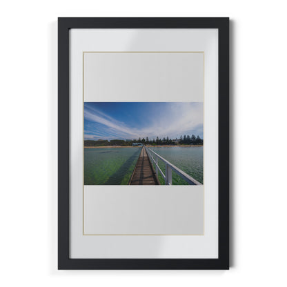 A beautiful jetty leading towards the shore over turquoise waters printed on a black framed poster