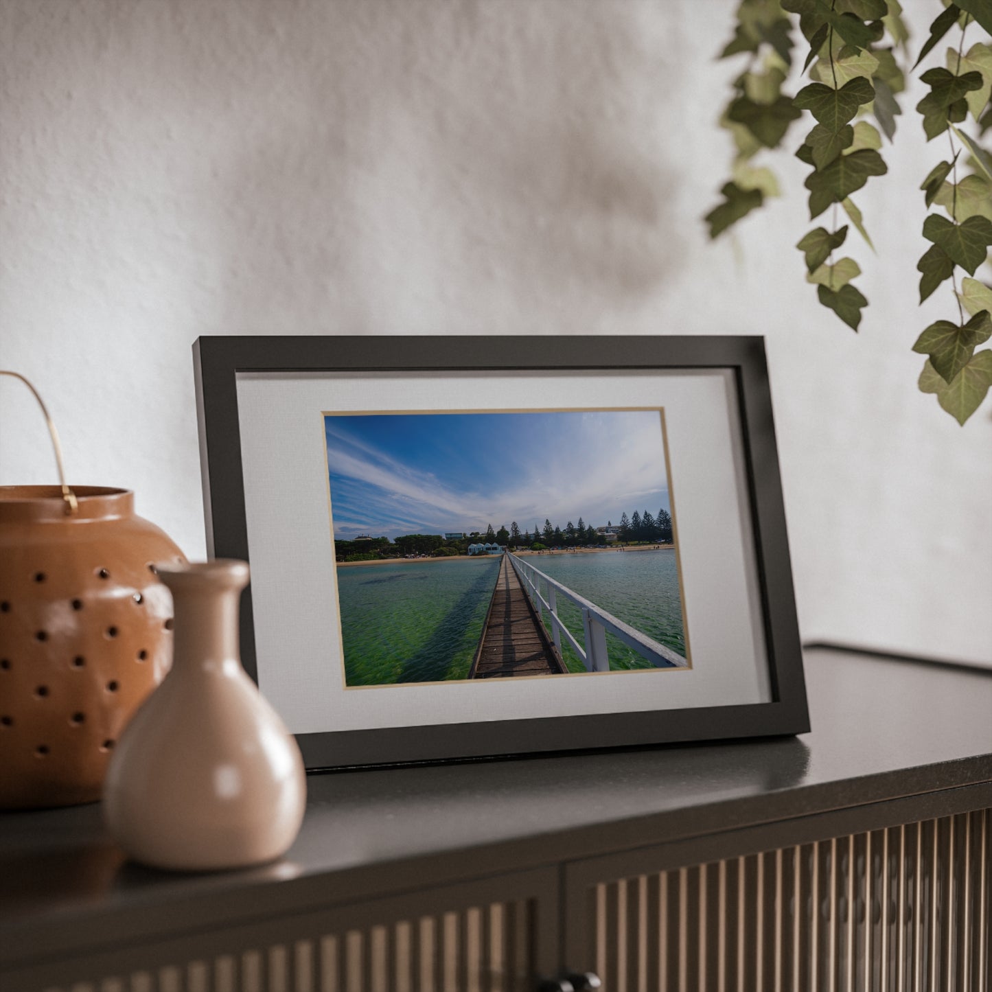 A beautiful jetty leading towards the shore over turquoise waters printed on a black framed poster