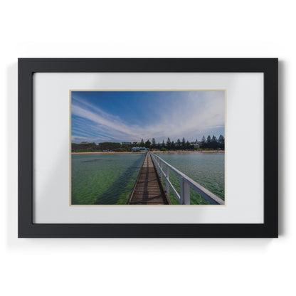 A beautiful jetty leading towards the shore over turquoise waters printed on a black framed poster