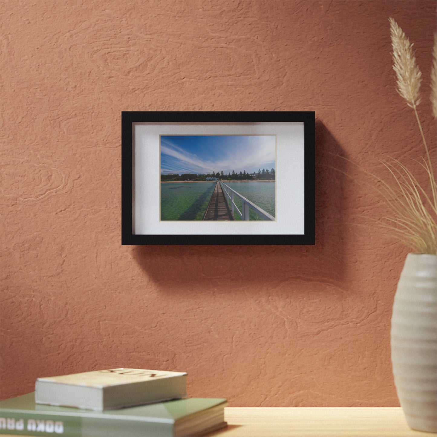 A beautiful jetty leading towards the shore over turquoise waters printed on a black framed poster